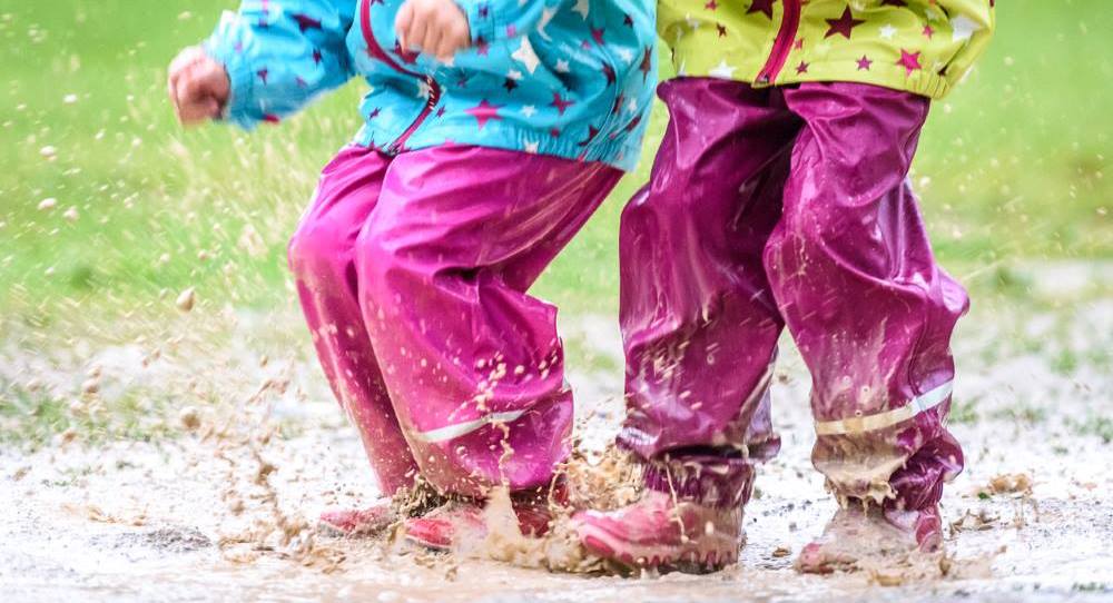 Children's Feet Splashing in a Puddle in a Yard with Poor Drainage